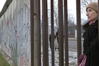 Viktoria Lomasko kijkt door een hek aan de voormalige Berlijnse muur