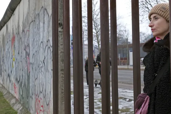 Viktoria Lomasko kijkt door een hek aan de voormalige Berlijnse muur