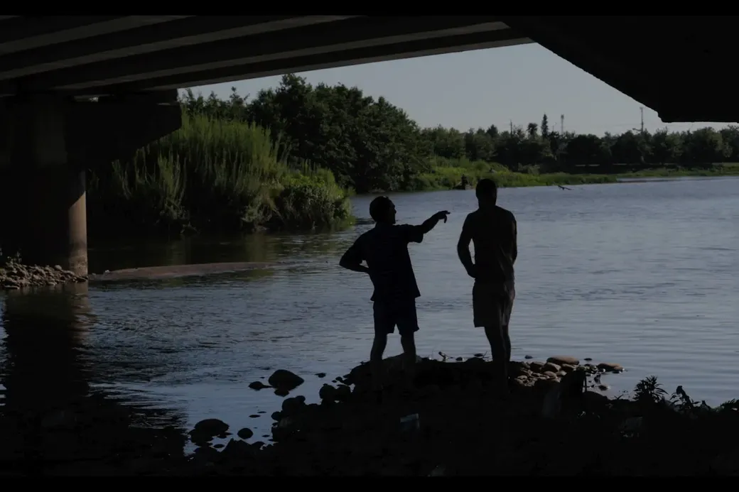 twee mannen staan onder een brug aan de oever van de rivier Engari