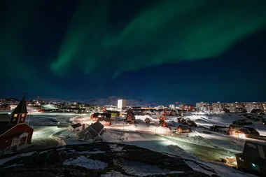 Nachtelijk zicht op Nuuk, de hoofdstad van Groenland. In de hemel is Noorderlicht te zien.
