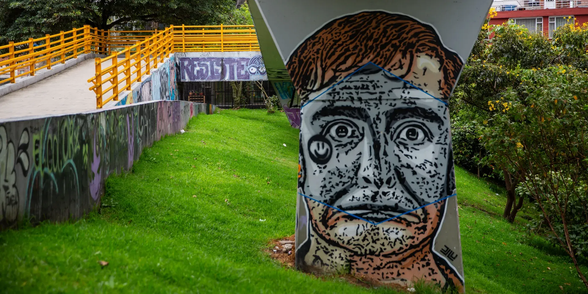 Het graffitiportret op de voorgrond stelt El Embolador voor, een personage van de Colombiaanse komiek, journalist, enfant terrible en vredesambassadeur Jaime Garzón. Met El Embolador zette hij politici geregeld in hun hemd. Garzón werd in 1999 op straat doodgeschoten door een paramilitaire militant, waarschijnlijk in opdracht van het Colombiaanse leger.
