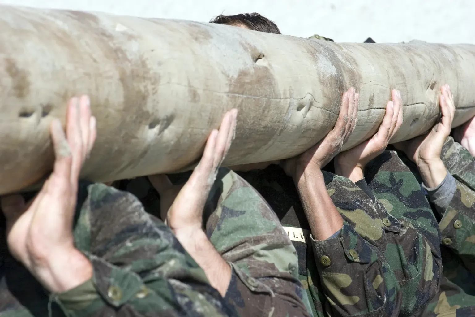 Soldaten dragen (onherkenbaar) een boomstam tijdens een militaire oefening
