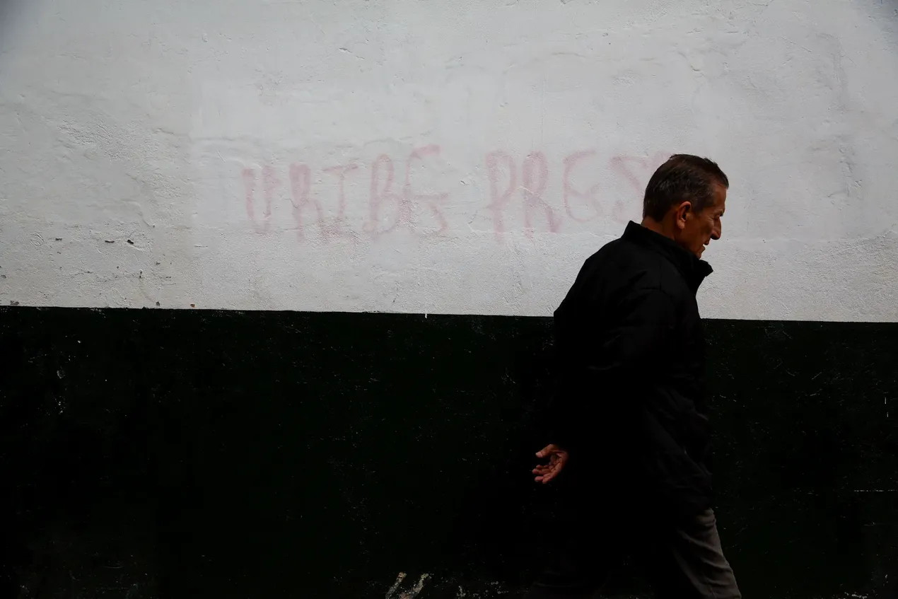 ‘Uribe gevangen’, staat er nog steeds, na een poging van het stadsbestuur om de tag te overschilderen. Álvaro Uribe was president tussen 2002 en 2010, en voerde een gecontesteerd beleid van “democratische veiligheid”, waarin de veiligheidssituatie aanzienlijk verbeterde, evenwel ten koste van een ongeziene terugval in burgerrechten. Het bekendste schandaal betrof de “valse positieven”, waarbij burgers werden vermoord door het leger en nadien werden voorgesteld als leden van de guerrilla.