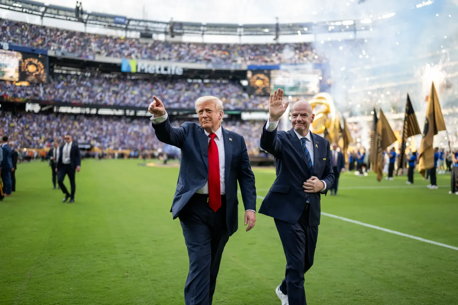 De aerikaanse president Trump en FIFA-voorzitter Gianni Infantino zwaaien naar supporters terwijl ze over een voetbalveld wandelen