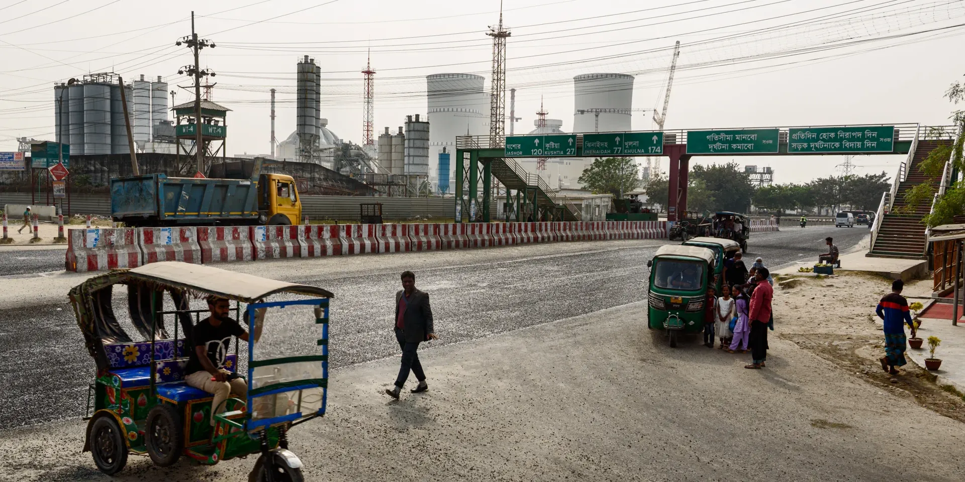 Een gezin wacht op een taxi aan het grote kruispunt tussen Little Russia en de kerncentrale van Rooppur. Het Bengaalse leger houdt een oogje in het zeil vanuit de groene uitkijktoren.