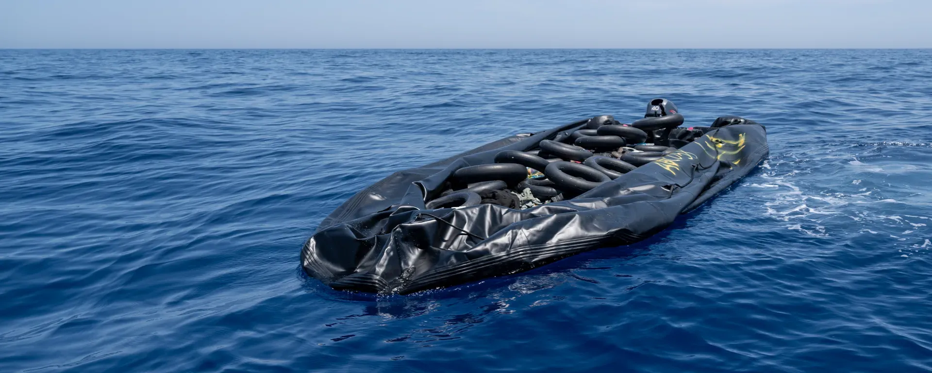Beeld van een half leeggelopen zwarte rubberboot in de Middellandse Zee