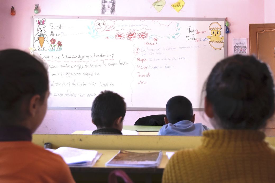 Koerdische kinderen in een klaslokaal. Op het bord staan Koerdische woorden