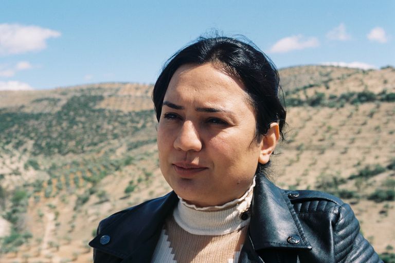 Een vrouw met in de achtergrond heuvels met olijfbomen