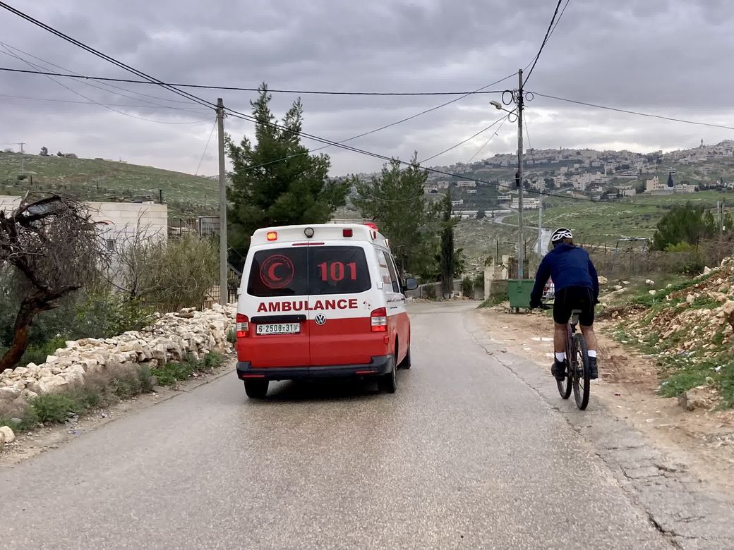 een ziekenwagen rijdt voorbij een fietser