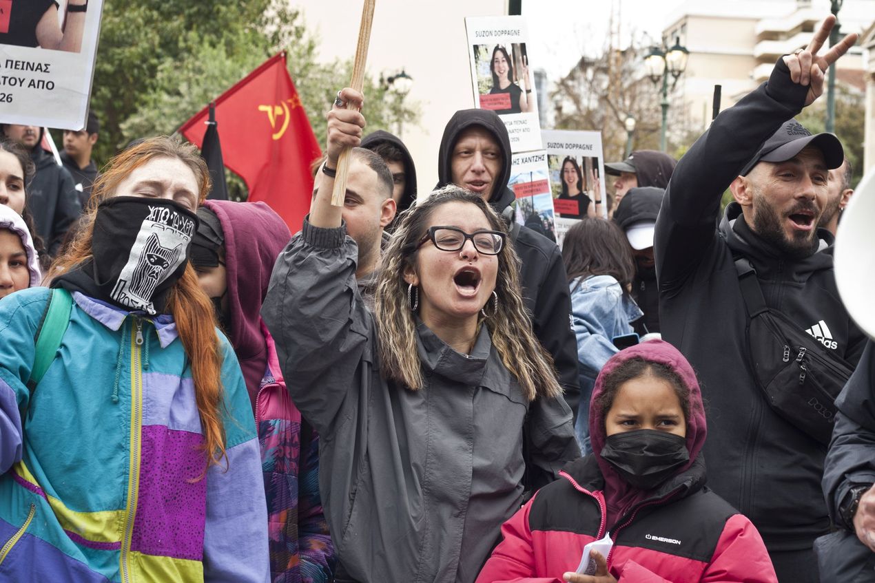 Bewoners van Prosfygika houden bordjes in de lucht en scanderen slogans op de 1 mei-betoging in Athene.