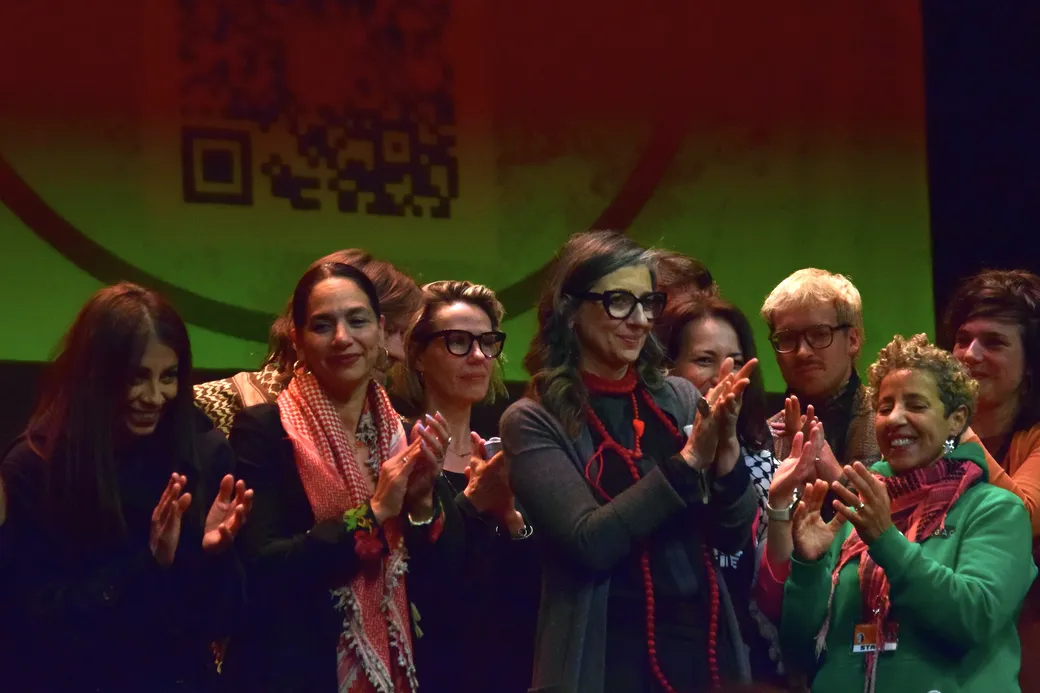 Noura Erakat staat samen met Fransesca Albanese en andere vrouwen applaudiserend op een podium