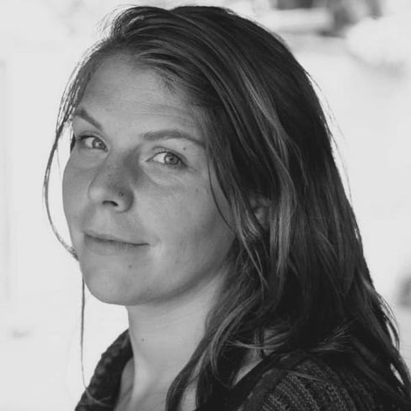 Black and white portrait of a person with long hair and a subtle expression, looking towards the camera.