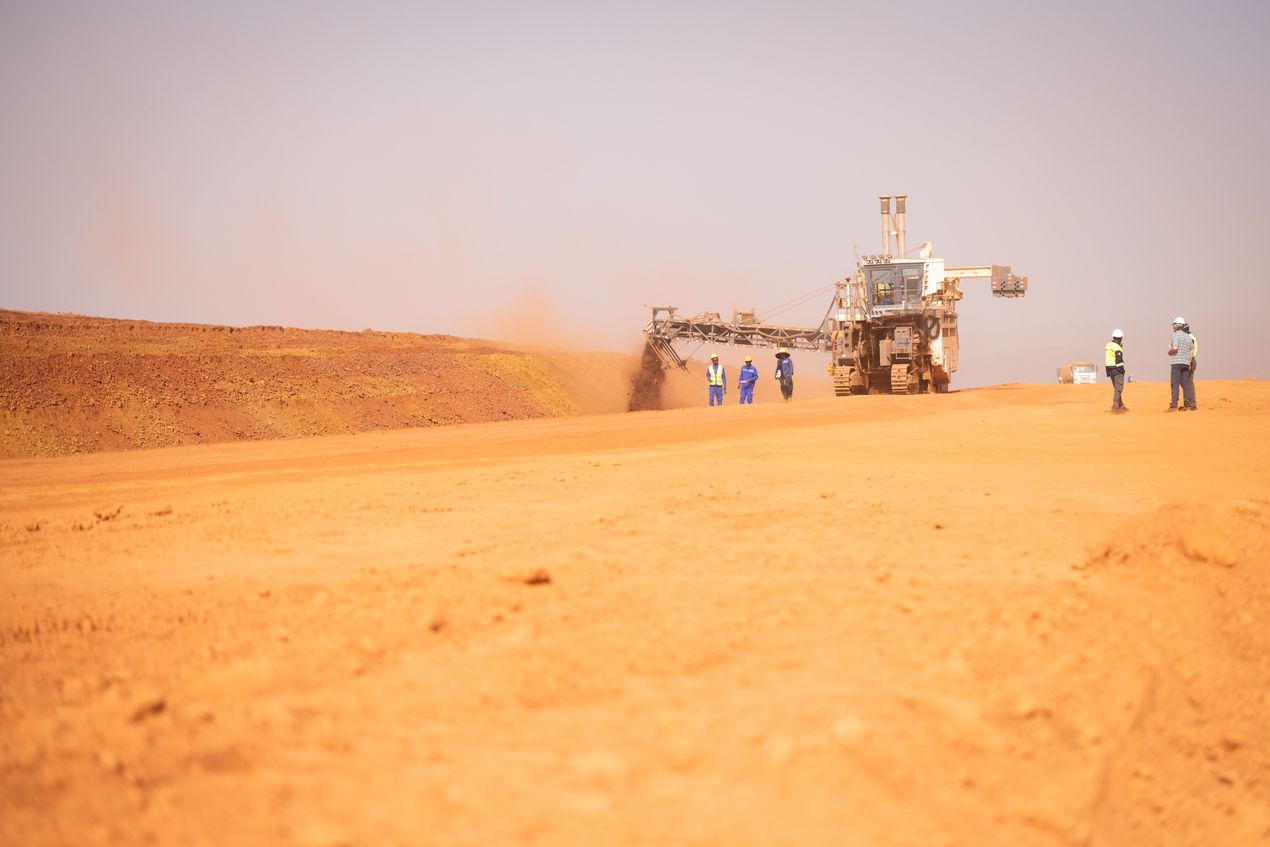 Een machine voor oppervlaktemijnbouw aan het werk in de zandvlakte van de Yellow River-mijn. Naast de machine staan enkele werknemers.
