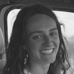 Smiling woman with long hair in a grayscale close-up portrait, sitting in a vehicle.