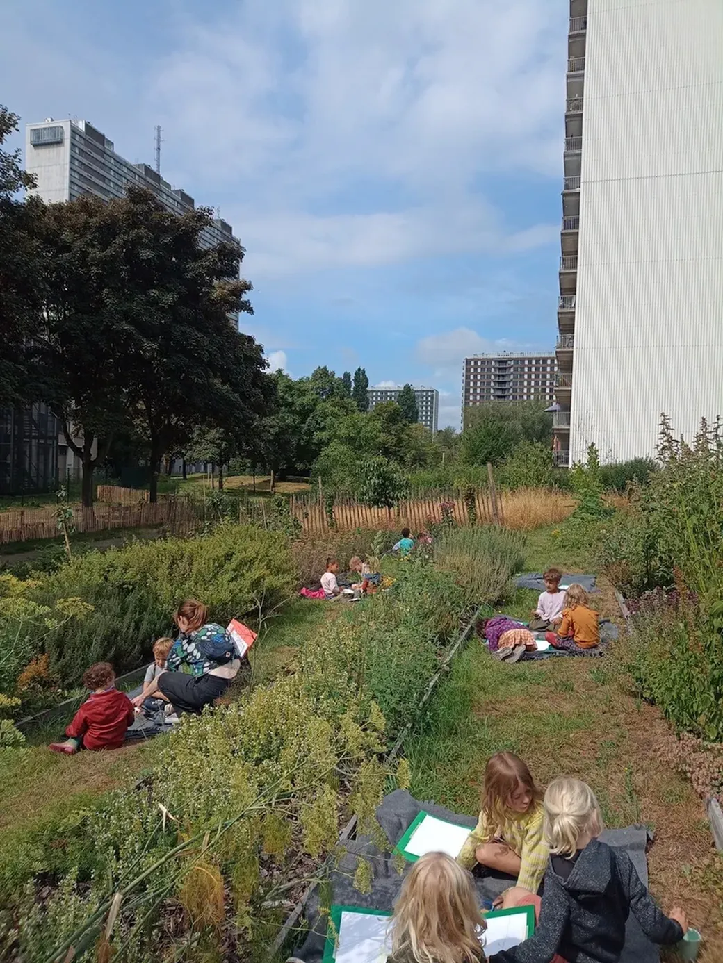 kinderen spelen op een “verwilderd” stuk grond voor een appartementsgebouw dat door ‘Plukgeluk’ bewust werd teruggegeven aan de natuur.