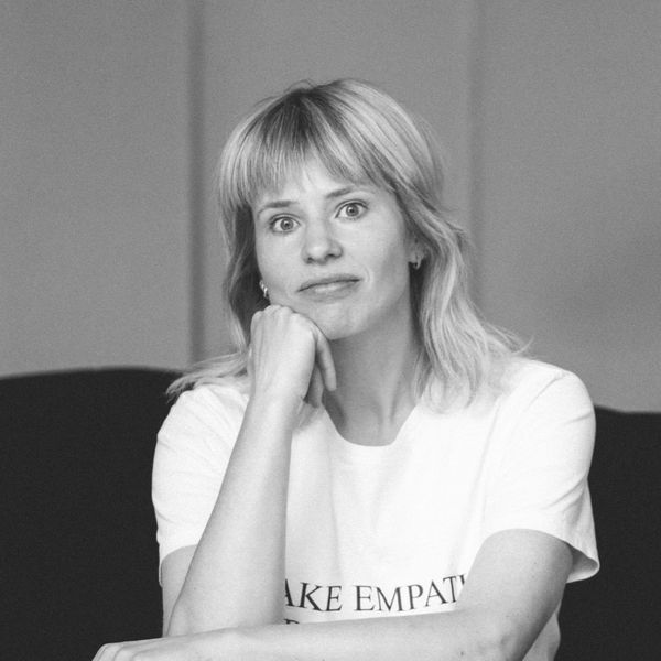 Black and white portrait of a person with chin resting on their hand, wearing a T-shirt, sitting with a thoughtful expression.