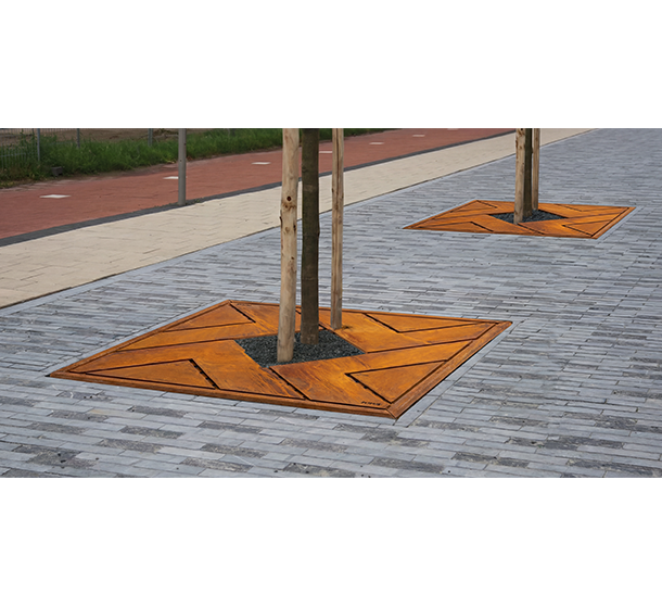 Trees planted in tiled urban spaces, surrounded by orange geometric grates on gray pavement, near a pedestrian walkway.
