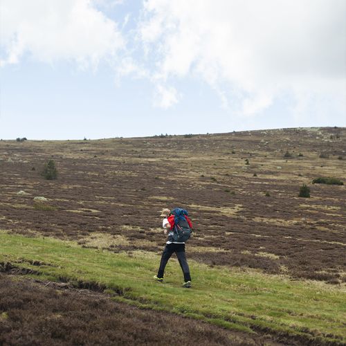 Personne en randonnée, sac au dos, avançant sur une crête dénudée du Mont Lozère - Atelier Tuffery