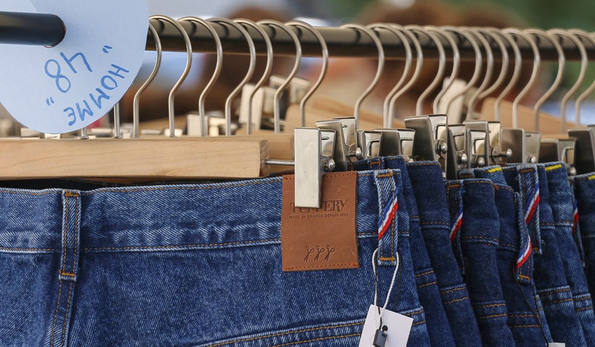Jeans en denim pour homme accrochés à un portant sur un stand Tuffery, étiquette de la marque visible. | Atelier Tuffery