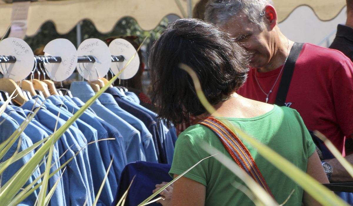 Clients regardant des chemises en denim pour homme sur un stand de marché en plein air | Atelier Tuffery