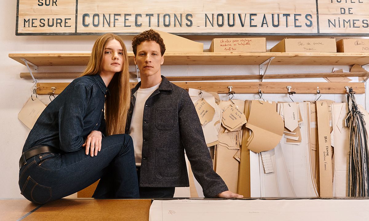 Femme et homme en tenues Atelier Tuffery posant devant un mur de patrons de couture. | Atelier Tuffery