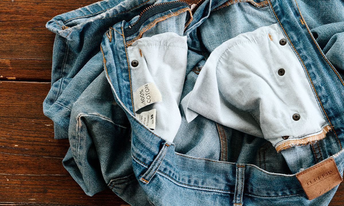Jean en denim ouvert, montrant l’étiquette intérieure “100% coton”. | Atelier Tuffery