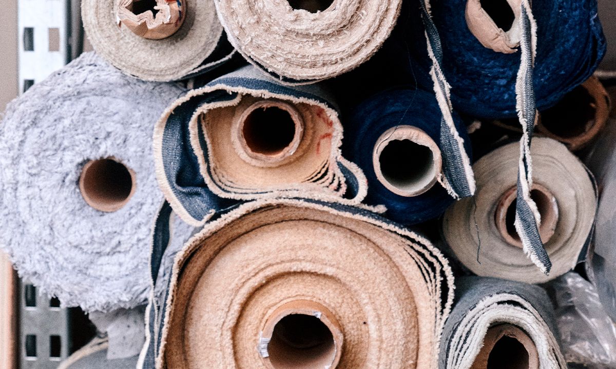 Rouleaux de tissus en denim et coton empilés dans un atelier. | Atelier Tuffery