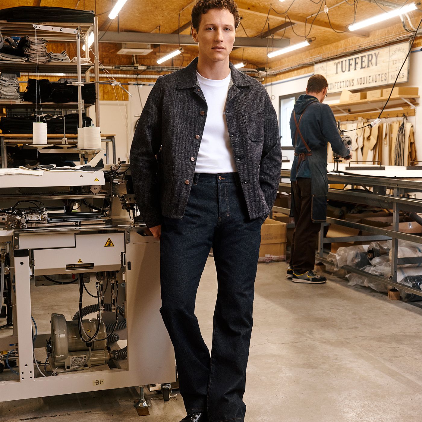 Homme portant veste et jean sombre dans un atelier de confection. | Atelier Tuffery