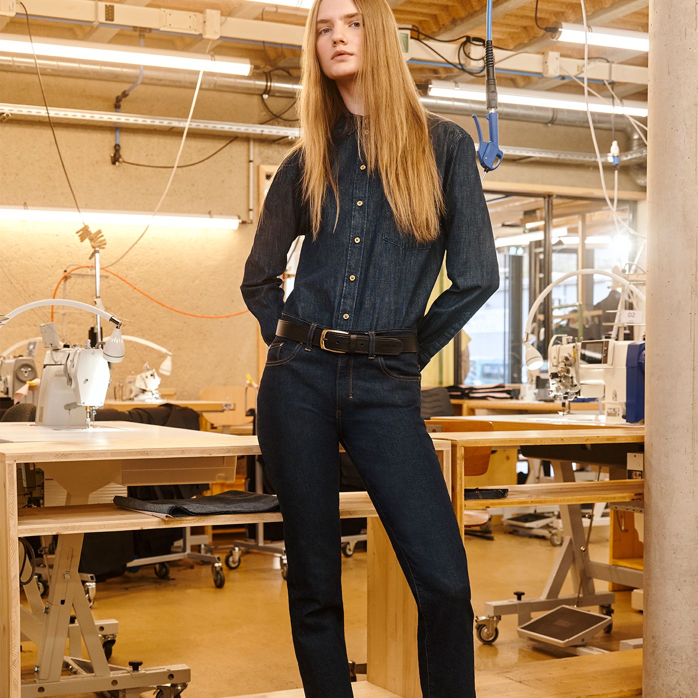 Femme en tenue en denim foncé posant dans un atelier de couture. | Atelier Tuffery