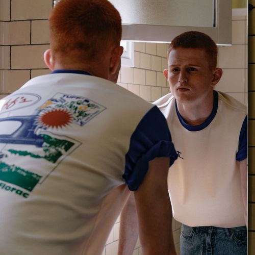 Mannequin portant un t-shirt blanc à manches bleues Atelier Tuffery devant un miroir. - Atelier Tuffery