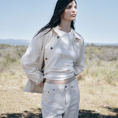 Femme portant une tenue claire dans un paysage de garrigue, entre herbes sèches, ombres d’arbres et lumière d’été. - Atelier Tuffery