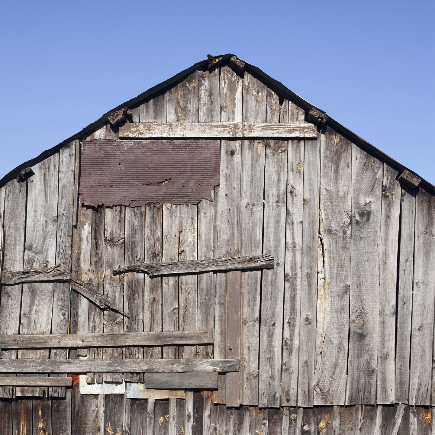 Grange ancienne en bois patiné, façade brute sous ciel bleu | Atelier Tuffery