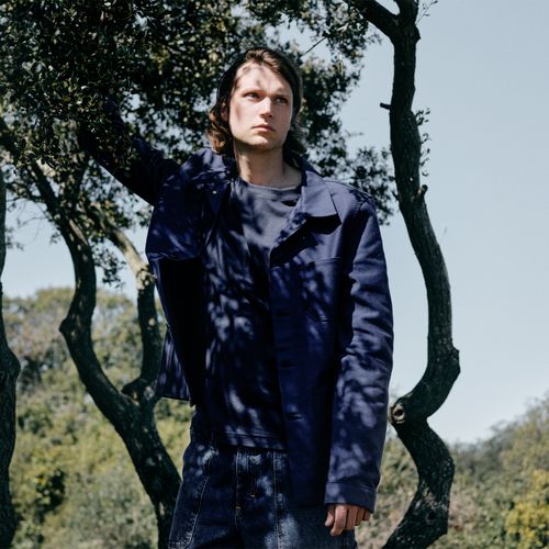 Homme portant une veste de travail bleu marine dans un paysage arboré. - Atelier Tuffery