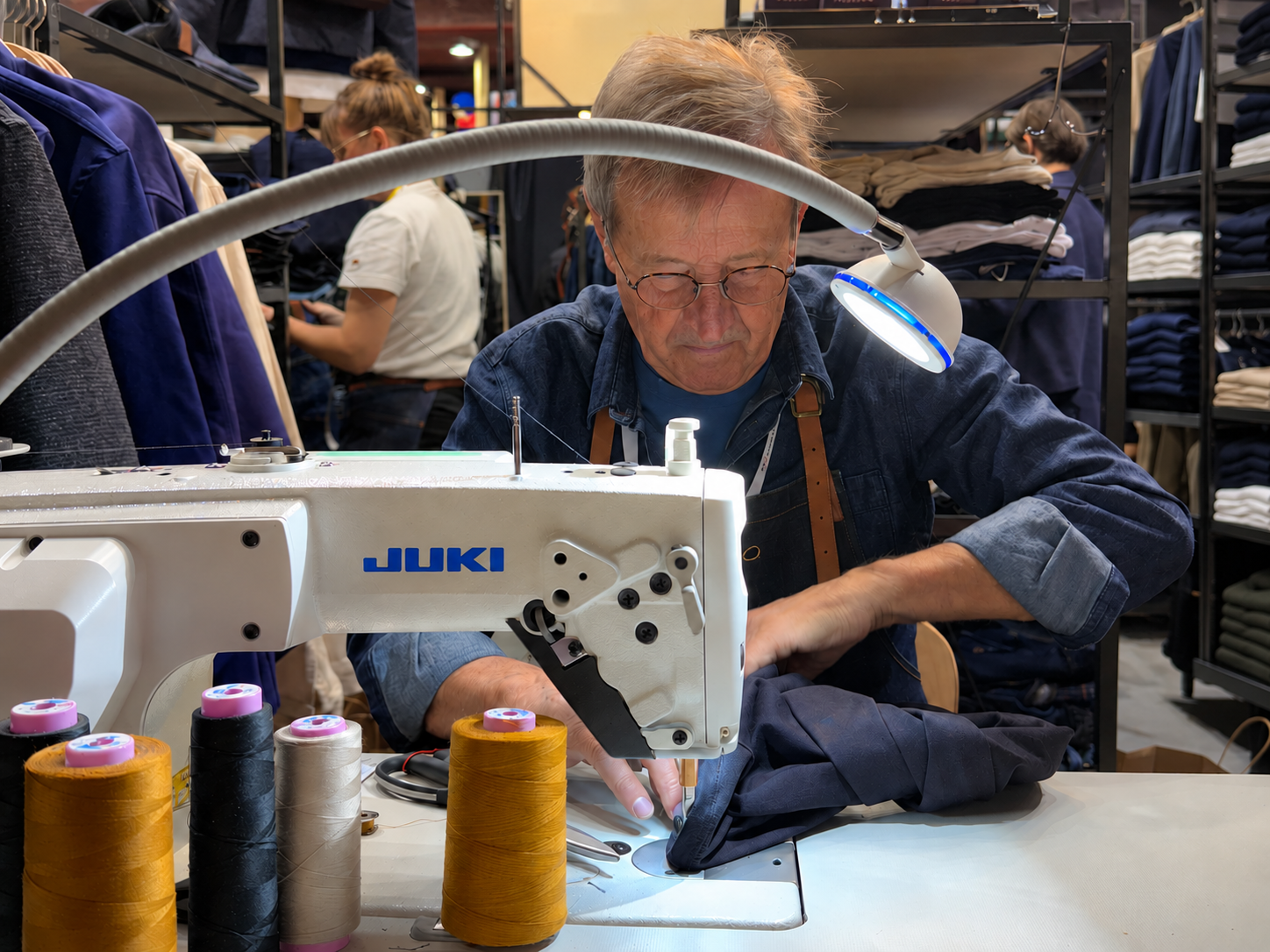Jean-Jacques Tuffery guidant un vêtement sous l’aiguille d’une machine à coudre lors d’une retouche. | Atelier TUFFERY