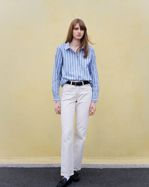 Modèle femme qui pose avec la chemise rayée et un pantalon blanc - Atelier Tuffery