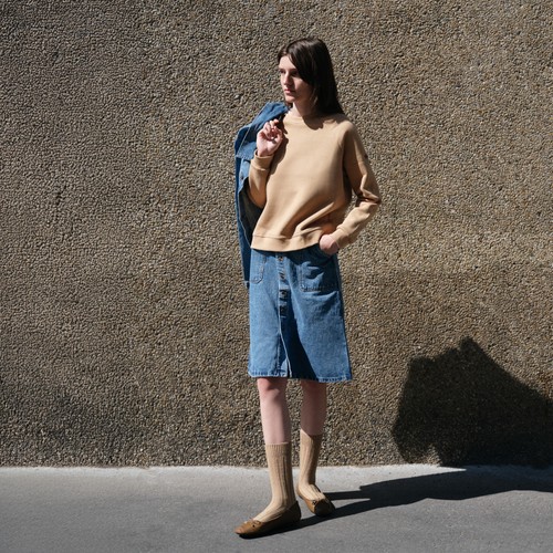 Une femme avec une jupe en jean clair, veste en jean et sweat en laine café - Atelier Tuffery