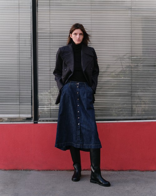 Une femme avec une jupe midi en jean stonewashed et manteau en laine - Atelier Tuffery
