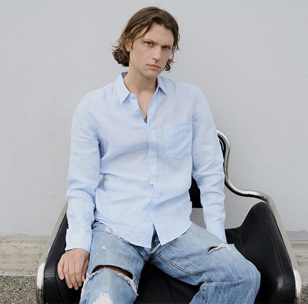 Homme assis portant une chemise bleu clair et un jean délavé déchiré | Atelier Tuffery