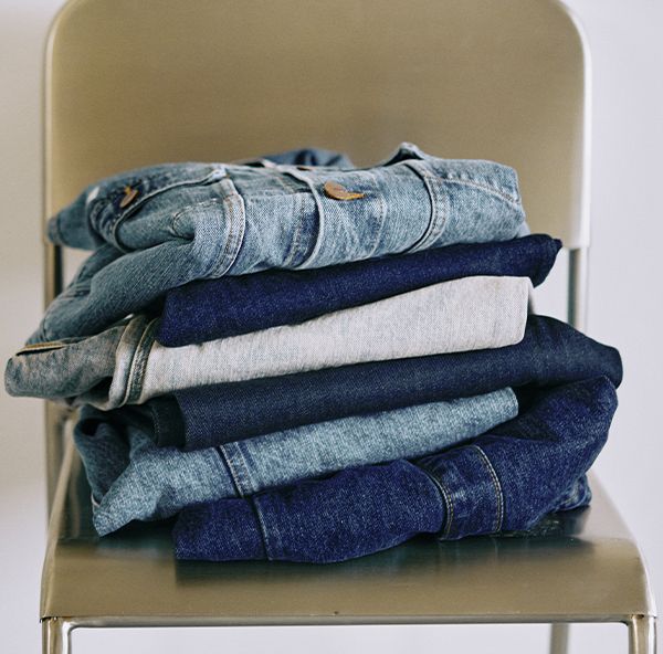 Pile de jeans en denim brut et délavé posée sur une chaise | Atelier Tuffery