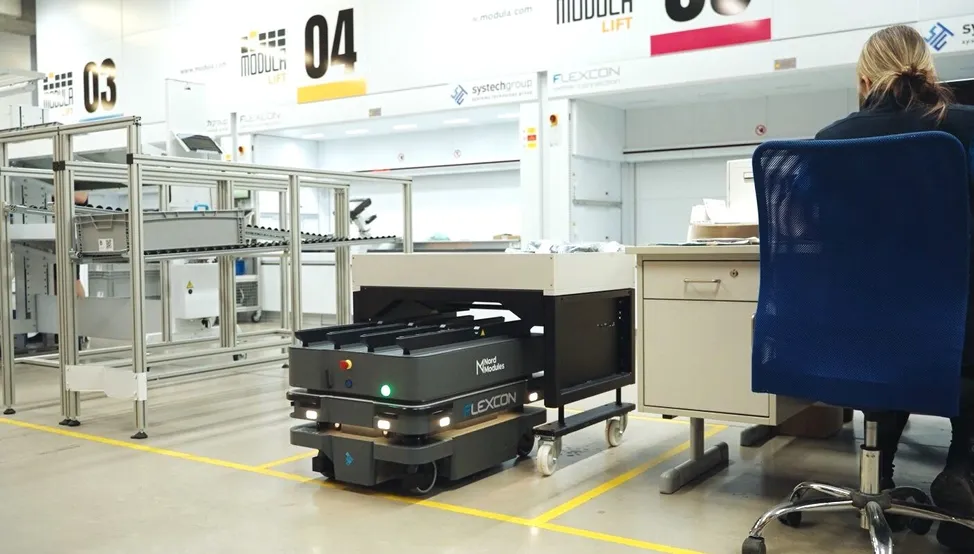 A fleet of MiR250 AMRs autonomously navigate the Flexcon facility to retrieve trays of parts from storage, delivering them to production without human intervention.