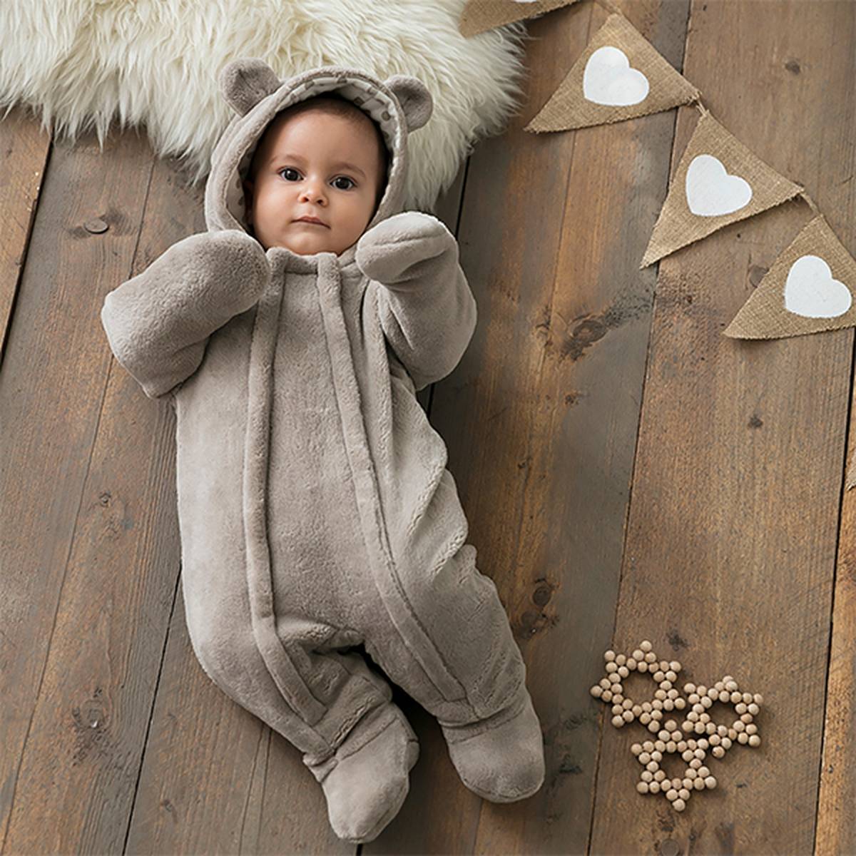 Ein Baby liegt auf dem Boden mit einem Strampelanzug mit Tierohren