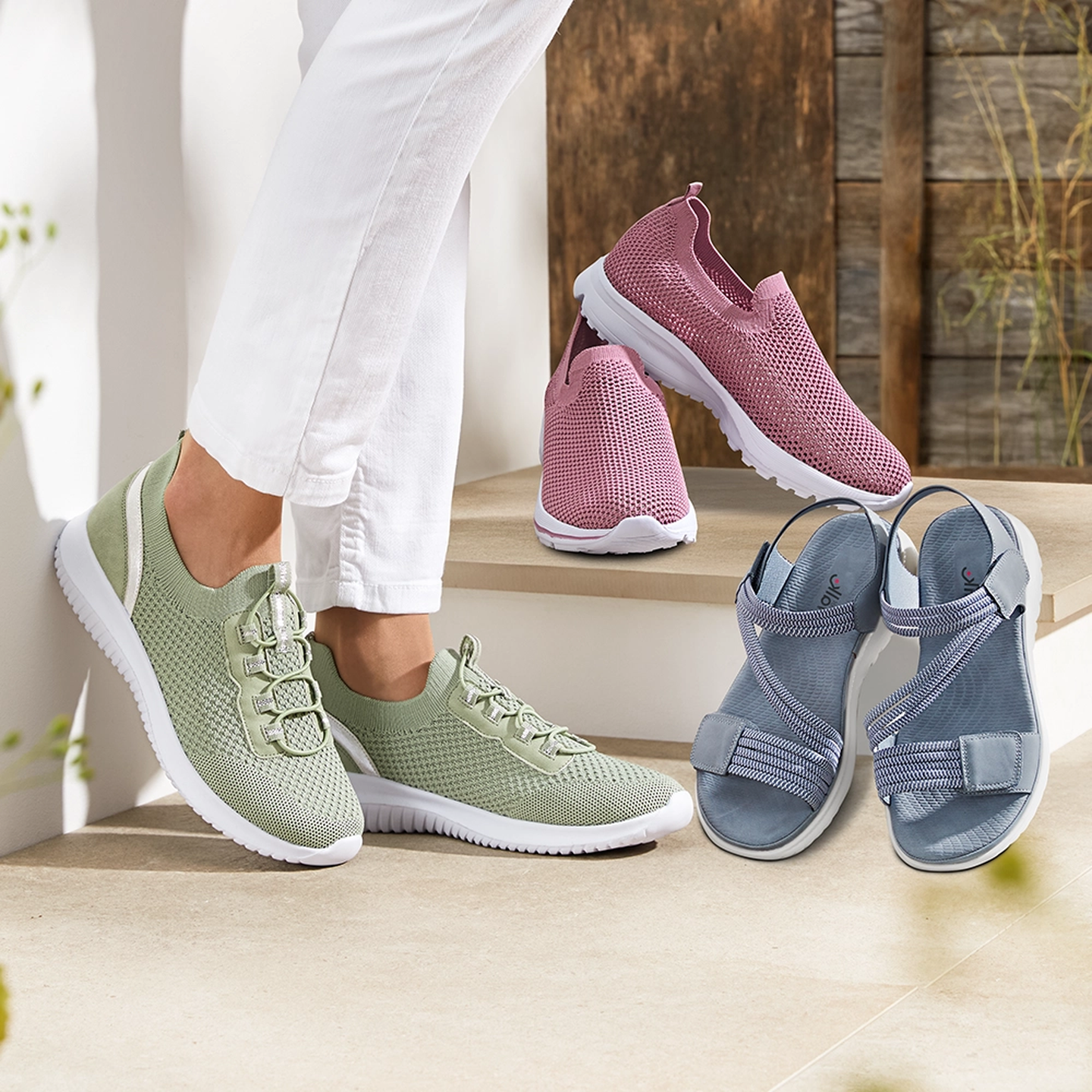 Trois paires de sandales Wonderwalk en beige, bleu et orange sur un patio ensoleillé. Une personne porte la paire beige. Prix : 29,99€
