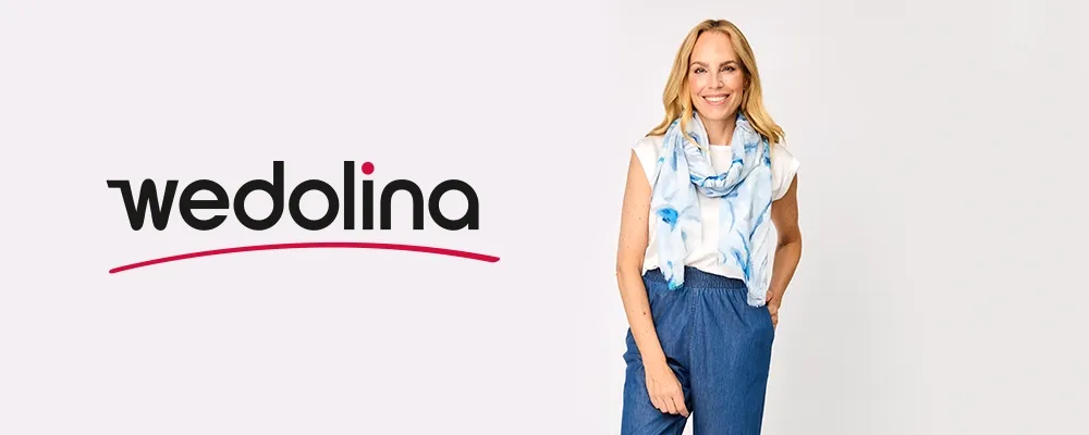 Lächelnde Frau in blauer Hose und weißem Oberteil mit blauem Schal steht neben dem „Wedolina”-Logo auf weißem Hintergrund.