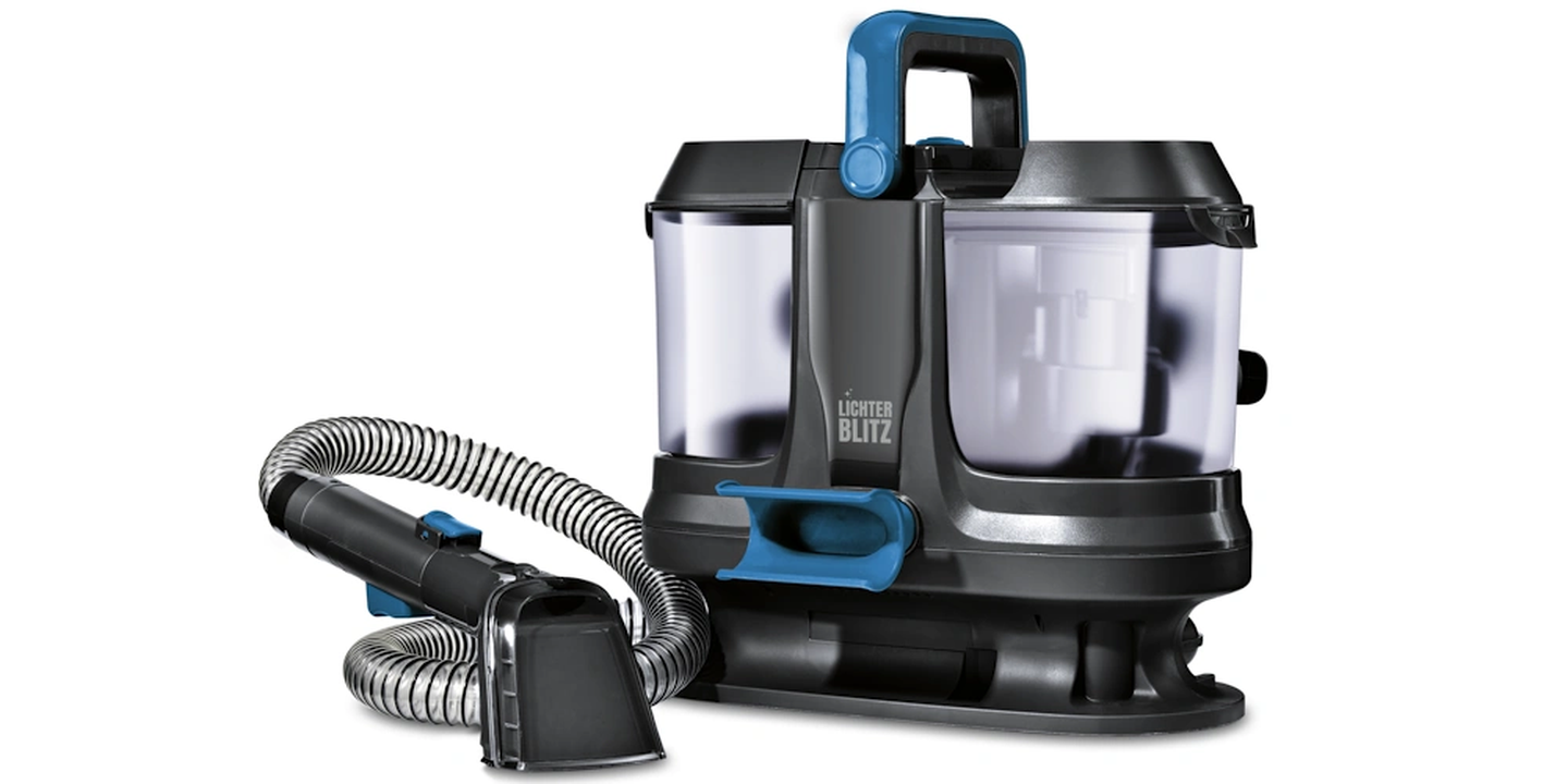 Ein kompakter, moderner Polster- und Teppichreiniger mit zwei durchsichtigen Wasserkammern, grauem Gehäuse, blauem Griff sowie einem angeschlossenen flexiblen Schlauch und einer Düse.