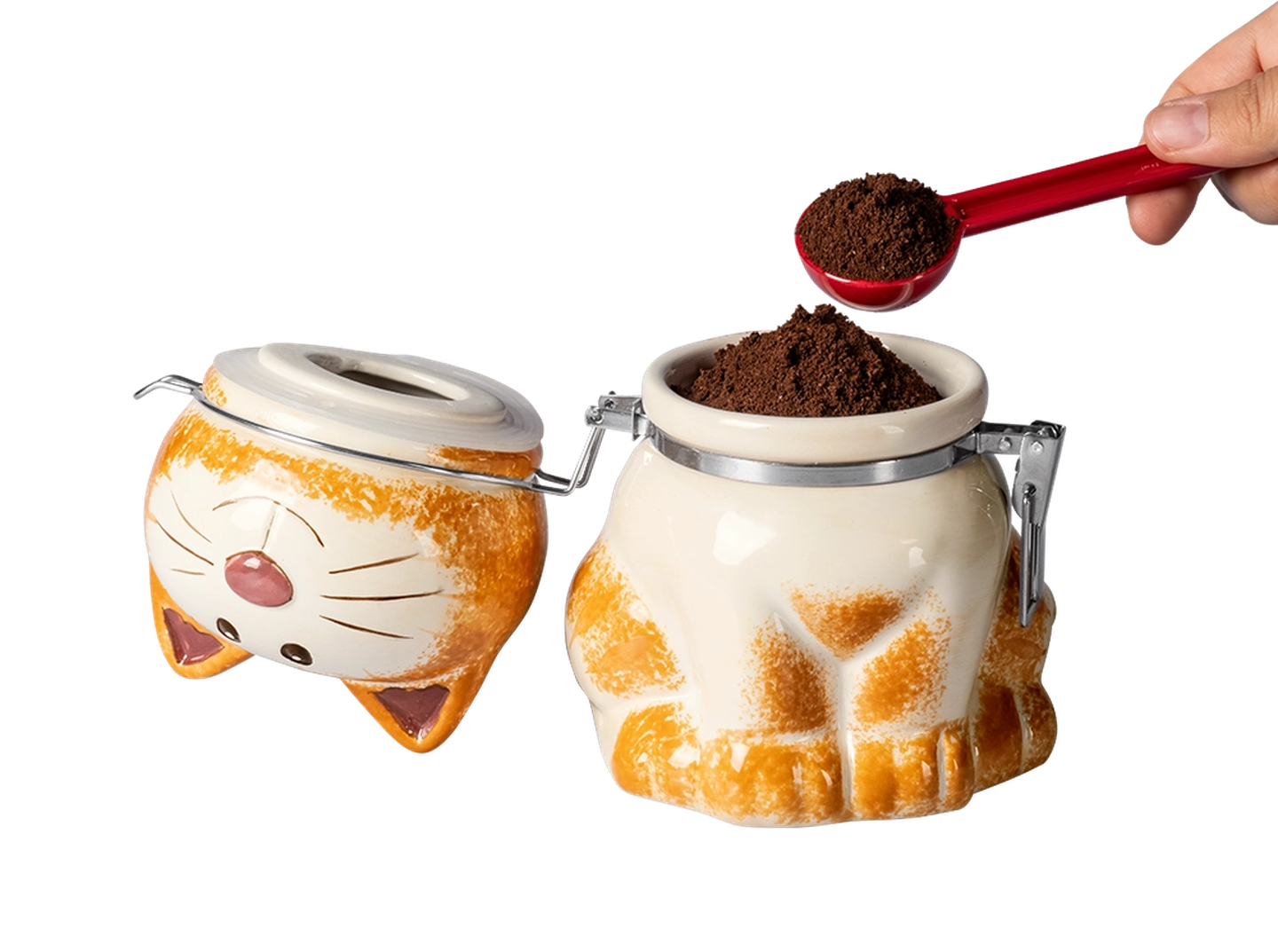 Keramikbehälter in Katzenform mit Deckel, gefüllt mit gemahlenem Kaffee. Eine Hand schöpft Kaffee mit einem roten Löffel.