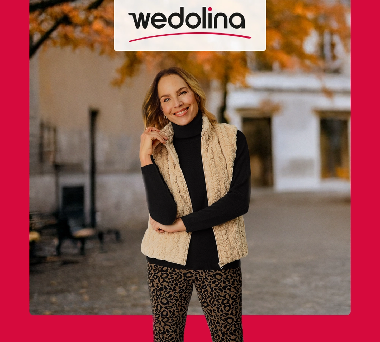 Eine lächelnde Frau in einer beigen Weste und einer Hose mit Leopardenmuster posiert im Freien vor dem Hintergrund von Herbstblättern. Über ihr ist ein „wedolina“-Logo zu sehen.