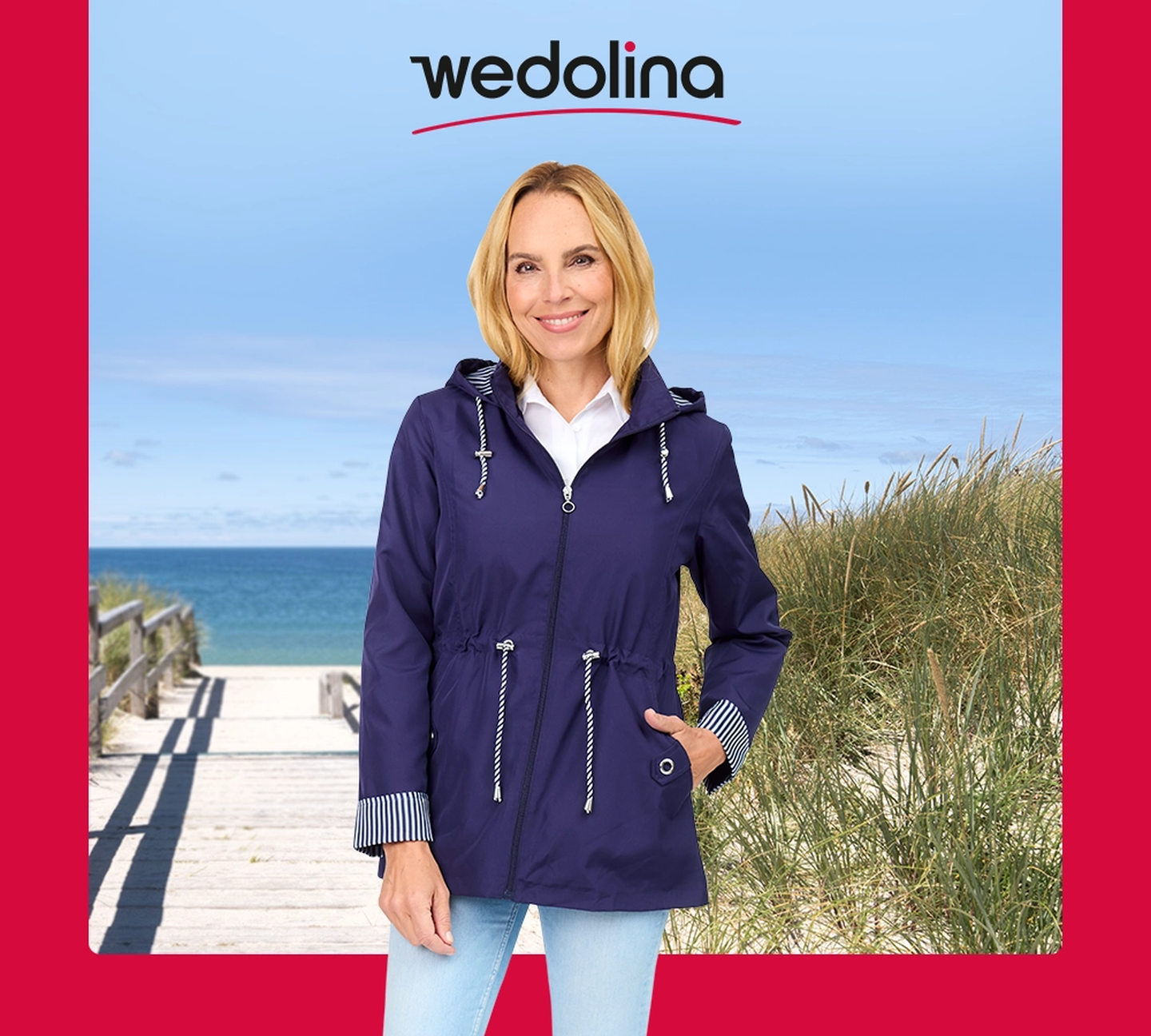 Eine Frau in einer blauen Jacke lächelt auf einer Promenade vor dem Hintergrund von Gras und blauem Himmel. Das „Wedolina“-Logo ist darüber gelegt.