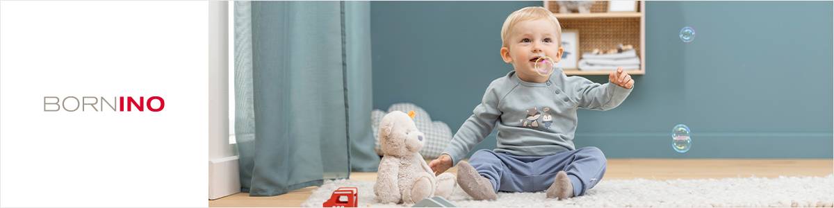 Ein Baby sitzt lächelnd auf dem Boden, umgeben von Spielzeug und Seifenblasen. Ein Plüschtier und ein kleiner roter Lastwagen stehen daneben. Links steht „BORNINO“.