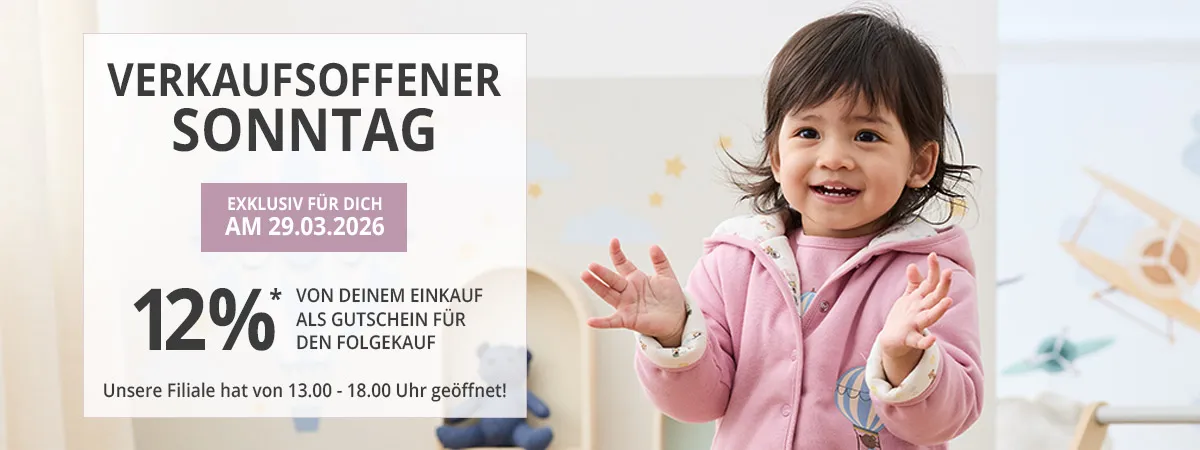 Kleinkind in einer rosa Jacke lächelt neben einem Schild, das auf eine Sonderverkaufsaktion am 29. März 2026 mit einem Rabatt von 12 % hinweist.