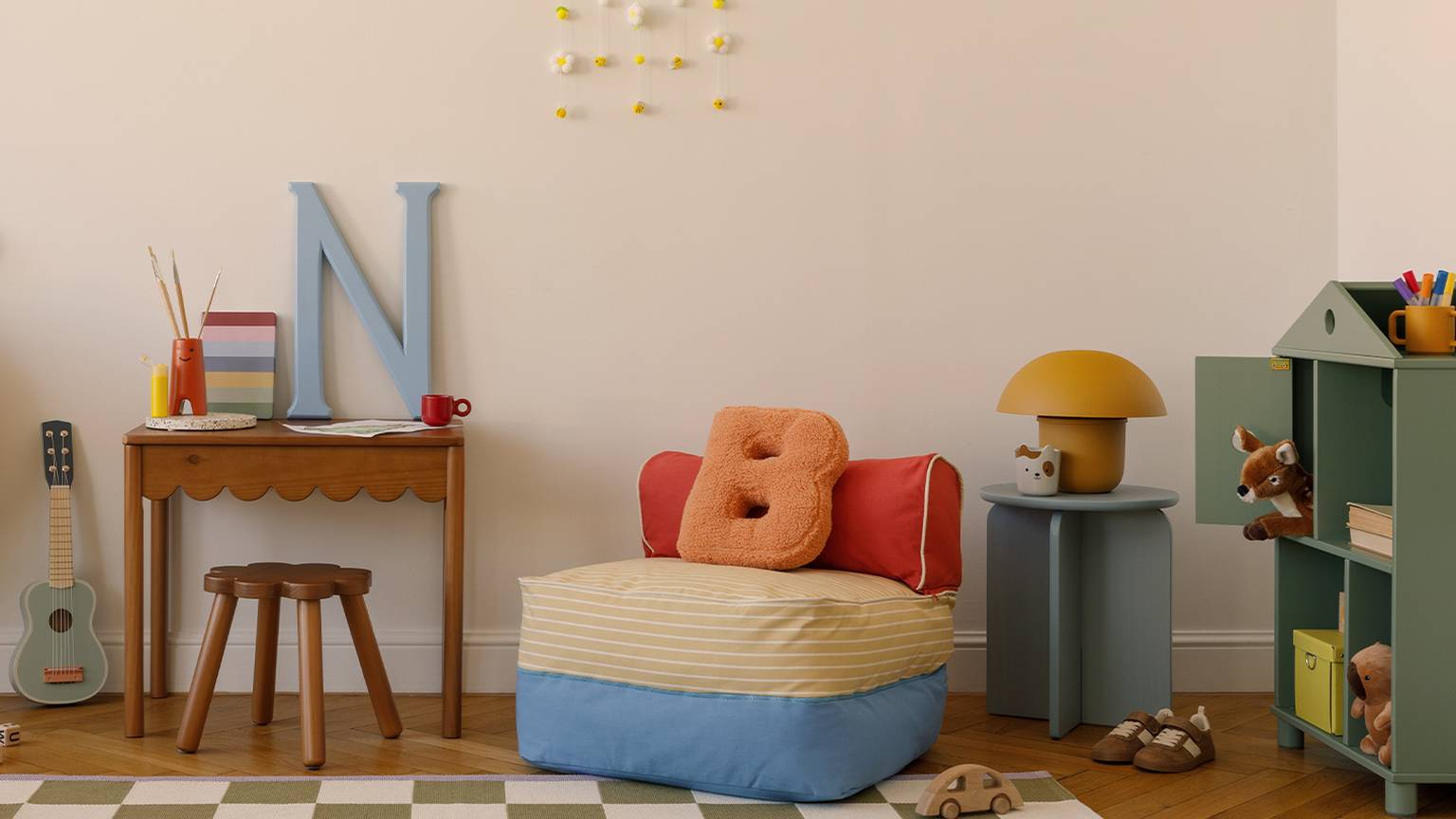 Gemütliches Kinderzimmer mit kleinem Schreibtisch, Sitzsack, Spielsachen und Dekoartikeln. Ein karierter Teppich bedeckt den Holzboden.